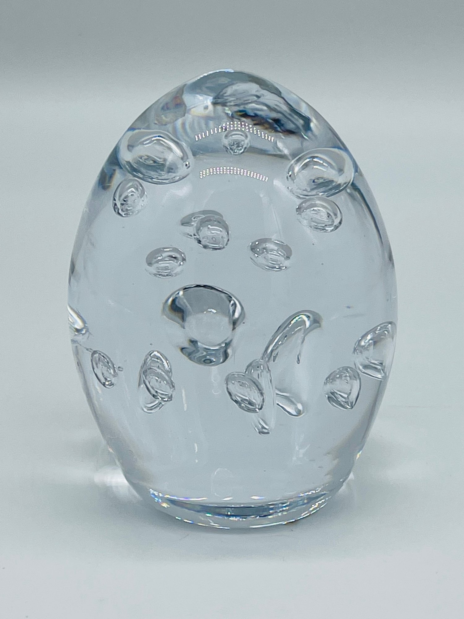 Clear art glass paperweight with bubble inclusions, side view